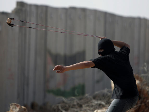 A Palestinian protester uses a slignshot to hurl a stone at Israeli troops, during a protest against Israel's separation barrier in the West Bank village of Nilin. 