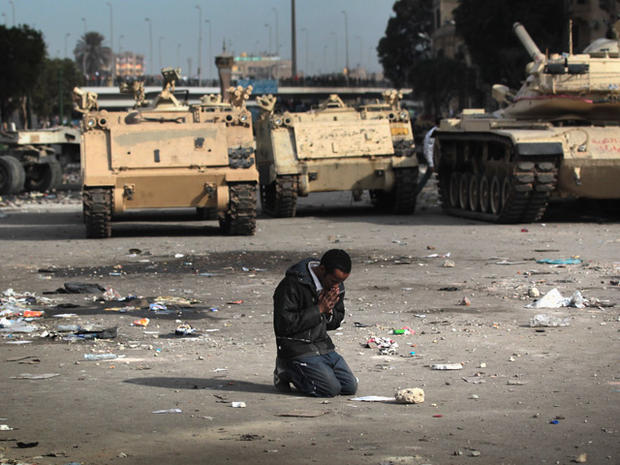 demonstrator prays near Egyptian army vehicles  
