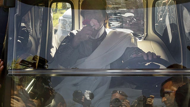 Libyan Leader Moammar Gadhafi smells flowers given to him by a supporter as he drives away in an electric golf cart after speaking in Tripoli, Libya, March 2, 2011. 