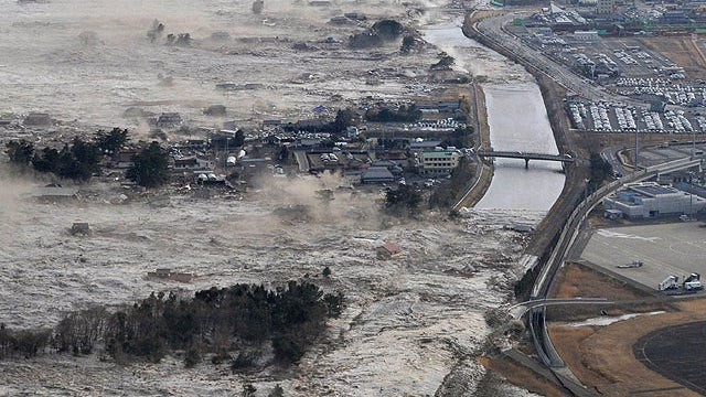 Earthquake-triggered tsunami waves sweep along Iwanuma in northern Japan on March 11, 2022.  