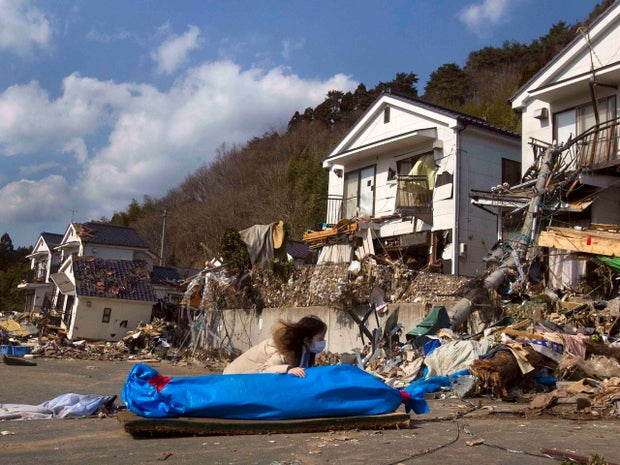 Tayo Kitamura, 40, kneels in the street to caress and talk to the wrapped body of her mother Kuniko Kitamura, 69, after Japanese firemen discovered the dead woman inside the ruins of her home in Onagawa, northeastern Japan Saturday, March 19, 2011. An 8.9-magnitude earthquake followed by a tsunami devastated the region on March 11. (AP Photo/David Guttenfelder) 