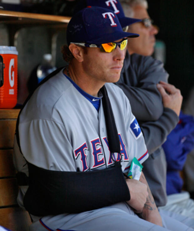 Josh Hamilton sits in the dugout with his right arm in a sling 