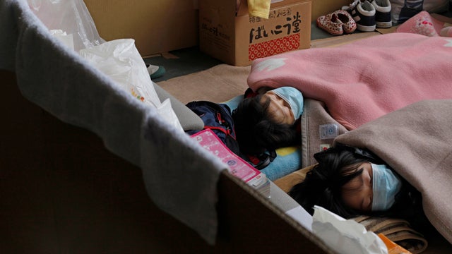 Tsunami-survivors sleep with masks at an evacuation center 