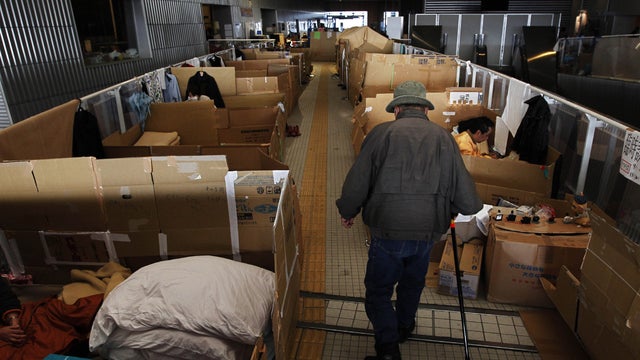 Japanese earthquake evacuee walks through a shelter 