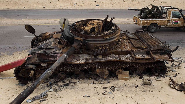 Libyan rebel fighters drive by a previously-destroyed pro-Gadhafi forces tank as they make their way to the frontline, on the outskirts of Ajdabiya, Libya, April 20, 2011.  