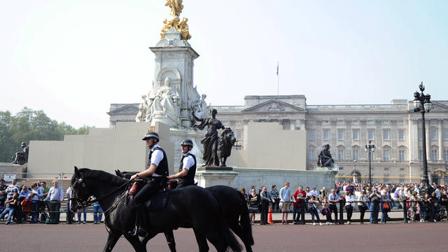 Mounted police patrol past Buckingham Palace  