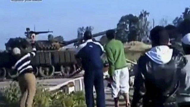 This video image taken from amateur video released by Sham News Network, a Syrian Freedom group, shows a man, left, preparing to throw an object at a tank as others look on, in Daraa, Syria Sunday April 24, 2011. The authenticity of the video could not be 
