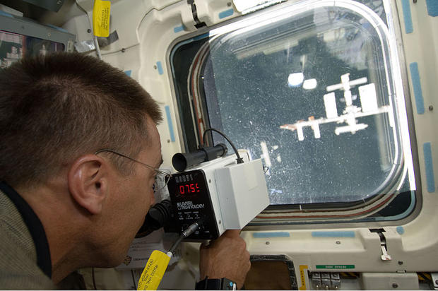 Endeavour astronaut Christopher Cassidy, STS-127 mission specialist, uses a range finding device to determine the distance between the shuttle and the International Space Station during docking activities on July 17, 2009 on a mission which delivered the  
