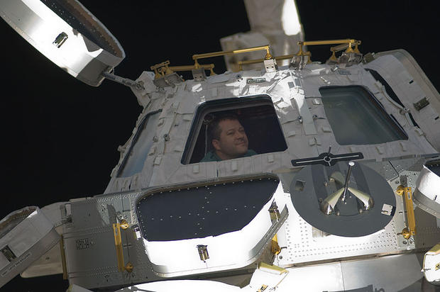 Astronaut Nicholas Patrick, STS-130 mission specialist, is seen looking through a window of the newly-installed 360 degree view Cupola of the International Space Station on February 18, 2010. 