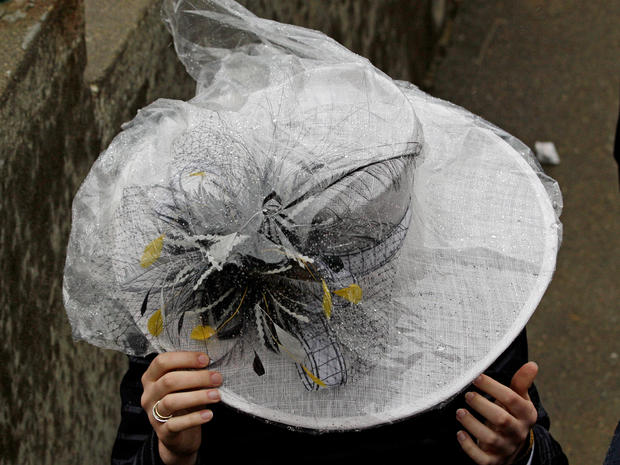 A woman protects her hat from the rain with a plastic cover before the 137th Kentucky Derby horse race at Churchill Downs, Saturday, May 7, 2011, in Louisville, Ky. 