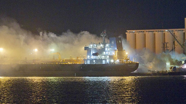Smoke and flames pour from the Libyan Navy frigate Al Ghardabia, right, after it was hit during an airstrike by Tornado bombers of Britain's Royal Force on the port area of Tripoli, in the early hours of May 20, 2011.  