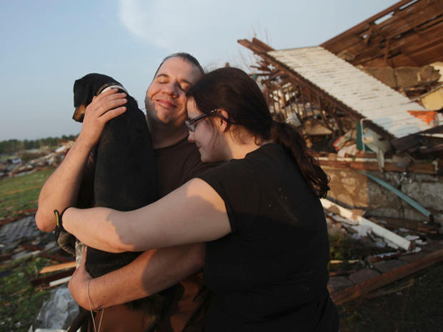 Maggie Kelley and Trey Adams hug their dog, Saint, after finding him amid the rubble 