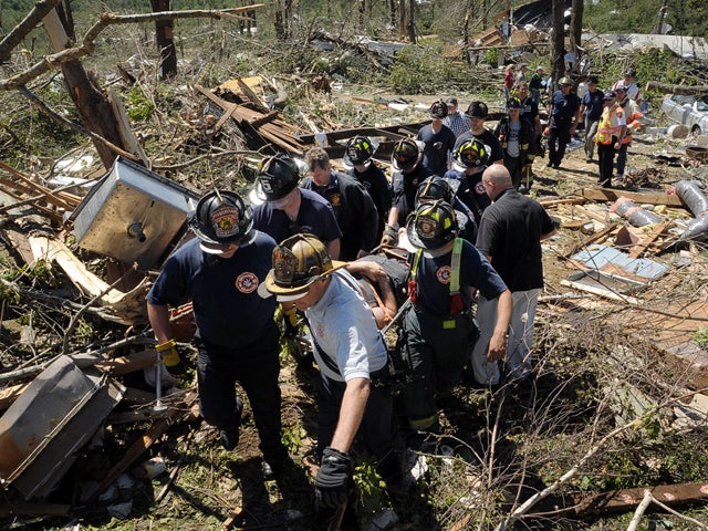 Firefighters carry an injured man through debris 
