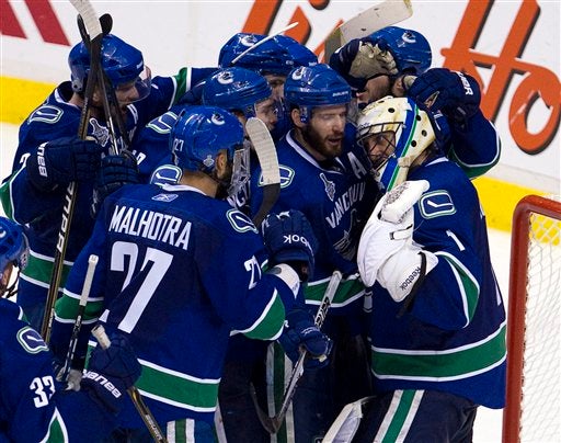 Canucks goalie Roberto Luongo is mobbed by teammates after defeating the Boston Bruins 