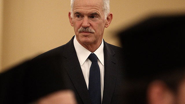 Greek Prime Minister George Papandreou stands between two Orthodox priests during a swearing in ceremony at the office of Greece's president, in Athens, June 17, 2011.  