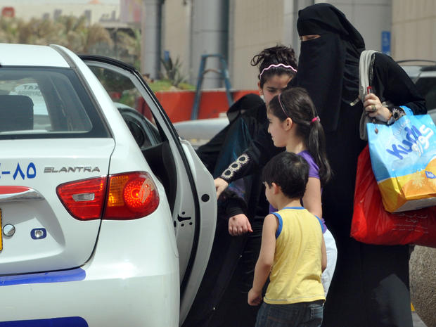 Saudi woman gets into a taxi with her children 