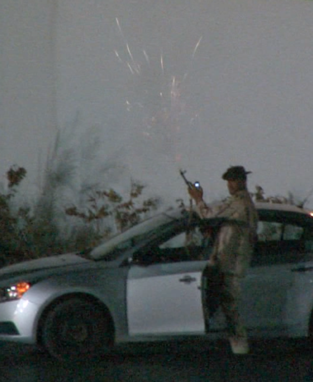 Qaddafi loyalist firing a gun in front of hotel. 