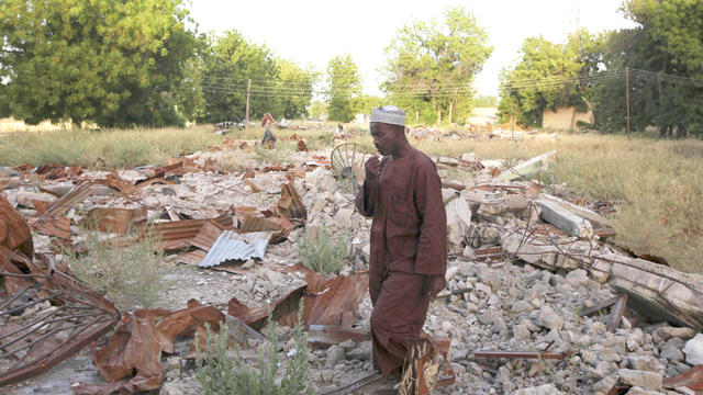 In this Nov. 12, 2010, photo, an unidentified man stand on the remains of the destroyed Boko Haram mosque in Maiduguri, Nigeria. While it may be apocryphal, many say this mosque's destruction gave birth to the Islamic extremist movement. 