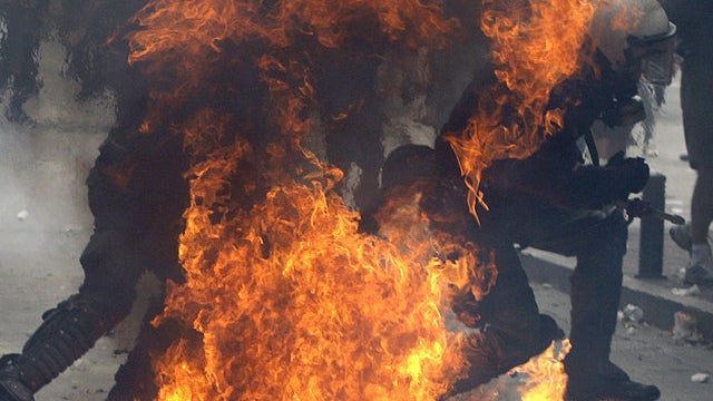 A fire bomb explodes as riot police officers run to avoid the fire during a demo in Athens on June 28, 2011.  