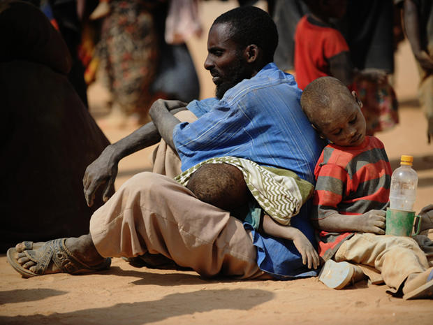 Somali man who fled violence and drought in Somalia with his family sits on the ground outside a food distribution point  