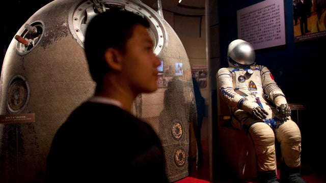 A visitor next to the Shenzhou 5 re-entry capsule at an exhibit in Beijing 