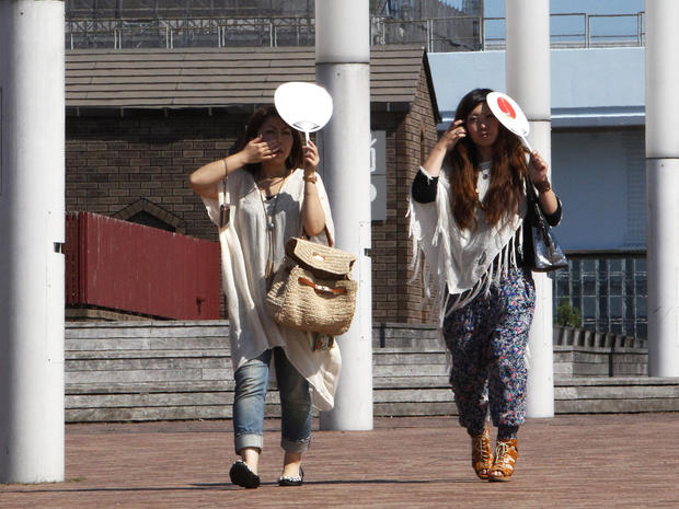 Women shield themselves from Tokyo sun with handheld fans 