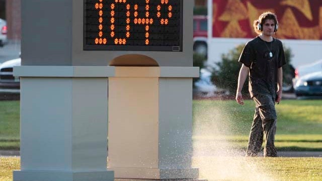 An unidentified pedestrian walks past a time and temperature sign in Lawrence, Kan., July 11, 2011. 