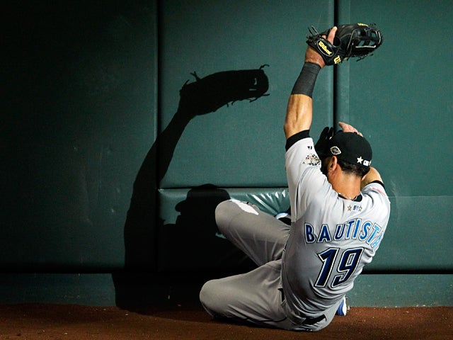 Jose Bautista slides into a wall after catching a foul ball  