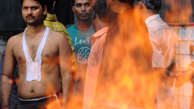 Indian mourner Mahant Mandal, left, watches the burning pyre of his brother, Kishan Mandal, after his death in a bomb blast at a crematorium in Mumbai, India, July 14, 2011. 