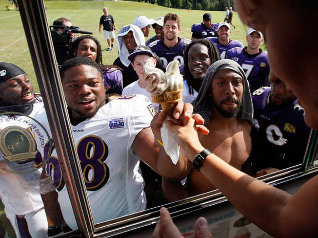 Gwynne Chapin hands an ice cream cone to Baltimore Ravens defensive tackle Bryan Hall  