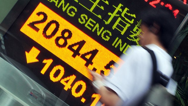 A man passes a display showing Hong Kong's Hang Seng Index 