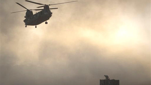  A US Marine tries to take cover, perched on a container, trying to shelter from the dust as a Chinook helicopter arrives to pick up supplies at Forward Operating Base Edi in the Helmand Province of southern Afghanistan, in this June 9, 2011 file photo. A 