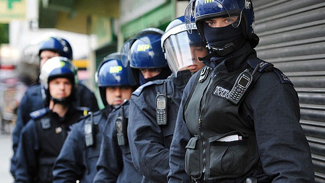 Metropolitan Police officers prepare to carry out a raid on a property on the Churchill Gardens estate in Pimlico, London during an operation where police hope to recover property stolen during the recent disturbances in the capital Thursday Aug. 11, 2011 