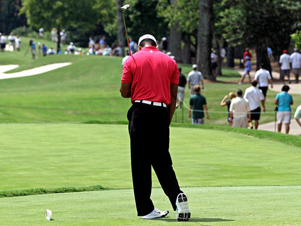 Tiger Woods reacts after hitting a drive  