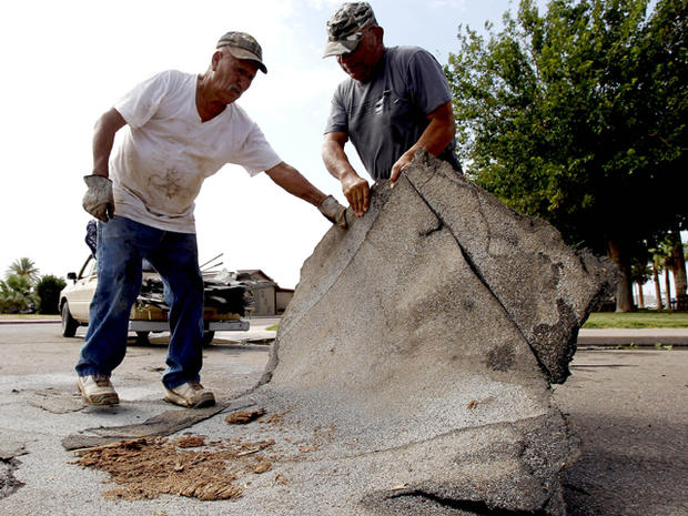 Enemencio Campos, right, and Pedro Lopez, both of Eloy, Ariz., pick up roofing debris Aug. 19, 2011, from the middle of an Eloy street the day after a violent storm hit the area. Pinal County authorities are assessing damage in Eloy after a summer storm rolled through, leaving behind a path of destruction. Homes were damaged, roofs were torn off businesses and a junior-high school had part of its roof missing. 