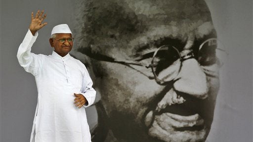 India's anti-corruption activist Anna Hazare waves next to a giant portrait of Mahatma Gandhi on the stage during his hunger strike in New Delhi,India, Saturday, Aug. 20,2011. Hazare said Saturday he was feeling physically weak but resolved in his demand  
