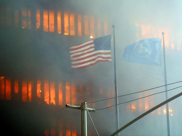 An American flag flies as one of the World Trade Center towers burns Sept. 11, 2001, in New York. 