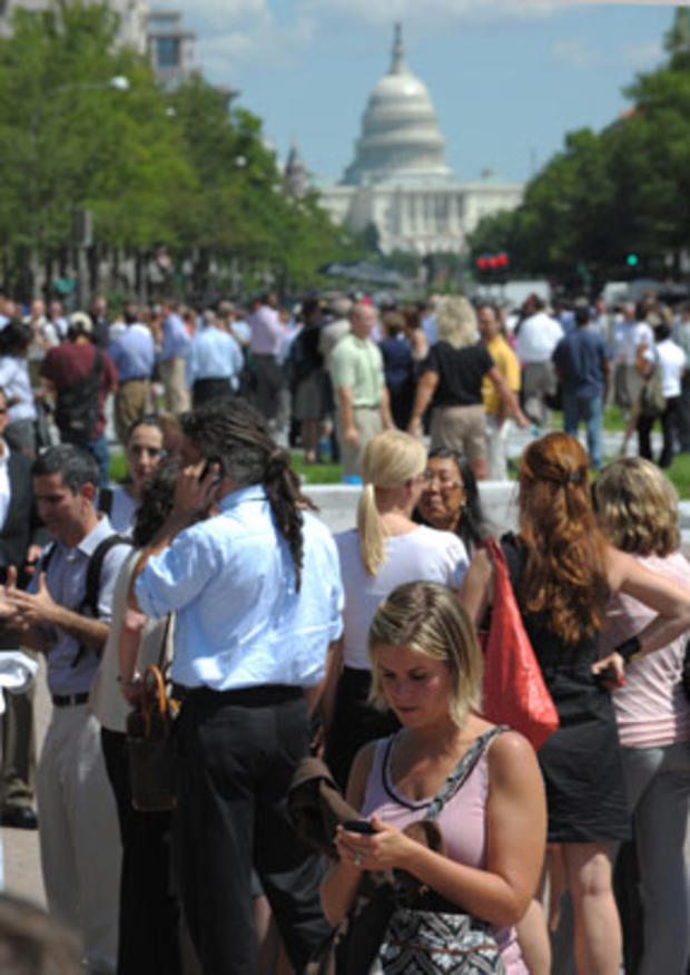 A woman checks her phone as office workers and others gather on Freedom Plaza after an earthquake was felt in Washington D.C. Aug. 23, 2011. 
