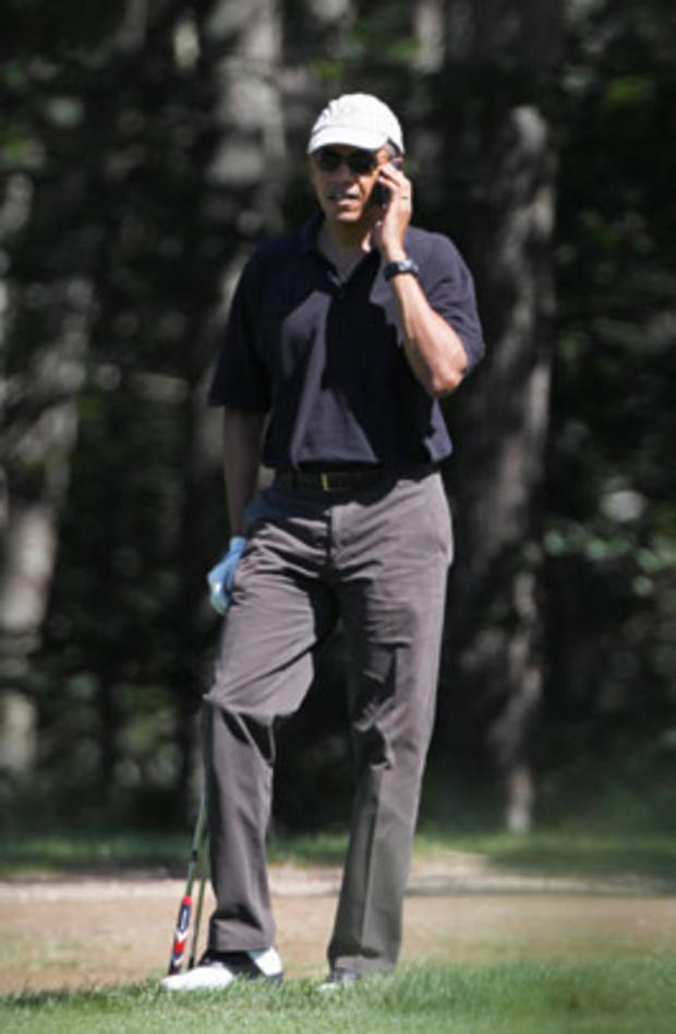 President Barack Obama takes a break from playing golf to speak on a mobile phone at Farm Neck Golf Club, in Oak Bluffs, Mass., on the island of Martha's Vineyard, Tuesday, Aug. 23, 2011. 