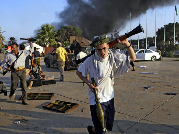 A rebel fighter carries a gun inside Muammar Qaddafi's main compound in Bab al-Aziziya in Tripoli, Libya, Aug. 23, 2011. Libyan rebels stormed Qaddafi's main military compound in Tripoli after fierce fighting with forces loyal to his regime that rocked th 