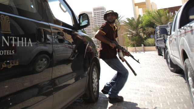 A Libyan rebel takes cover as Tripoli's central Corinthia Bab Africa Hotel, where numerous foreign journalists are based, came under attack Aug. 25, 2011. 