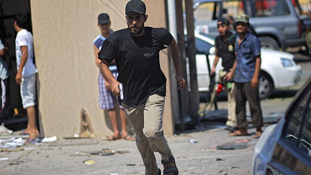 A Libyan man runs across the street seeking shelter from sniper fire in Tripoli, Libya, Aug. 26, 2011.  