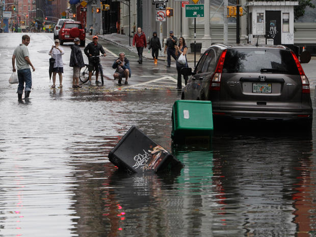 People take photos of a car parked on the flooded intersection of West Broadway and Grand St. 
