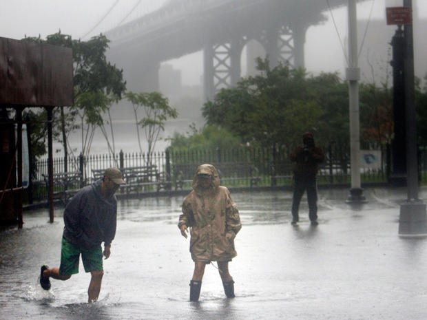 people wade through a flooded area near the Brooklyn Bridge  