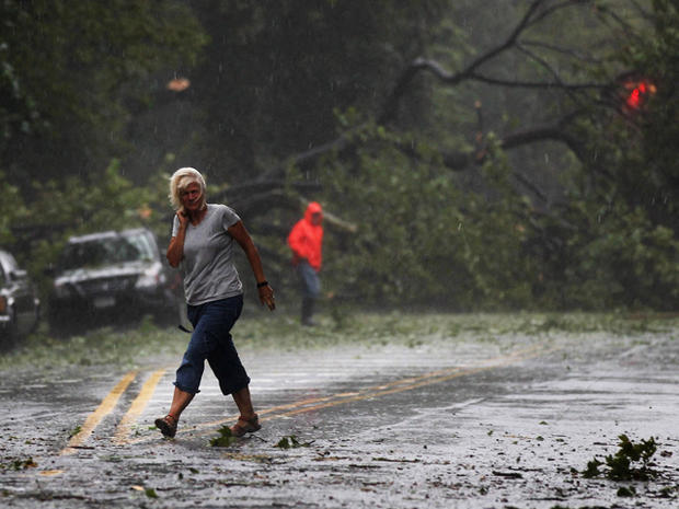 A woman walks by downed trees 