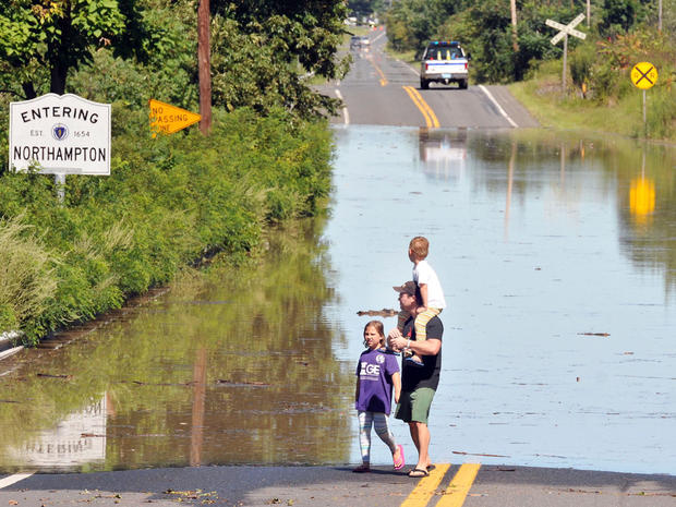 Mark Lussier, with son Rowan, 6, on his shoulders and daughter Charlotte, 8, all of Holyoke, Mass., walk beside a flooded portion of Route 5 near the Northampton  and Easthampton, Mass., line Aug. 29, 2011. 