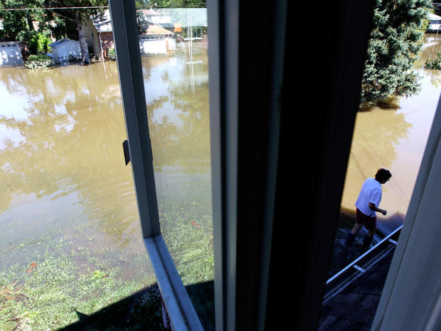 Chris Arnowitz, 65, is seen through the crack of the window on the second floor of her home as she walks in floodwaters in Pompton Lakes, N.J.,  