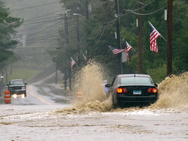 A car makes its way across a wide stretch of flooded roadway on Rt. 30 in Newfane, Vt. 
