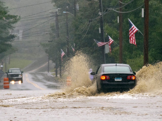 A car makes its way across a wide stretch of flooded roadway on Rt. 30 in Newfane, Vt. 