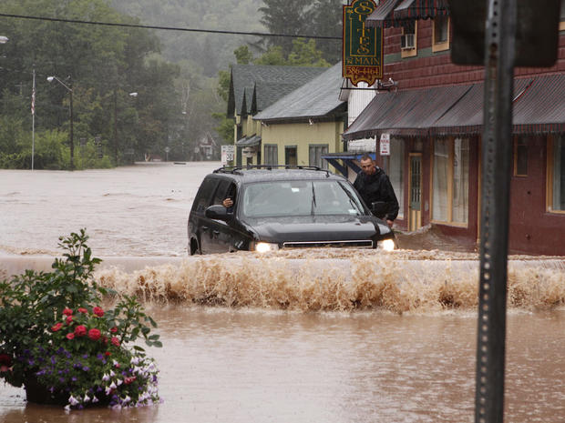 A security guard hangs on the door of Gov. Andrew Cuomo's SUV in the middle of a flooded street Sunday, Aug. 28, 2011, in Margaretville, N.Y. 